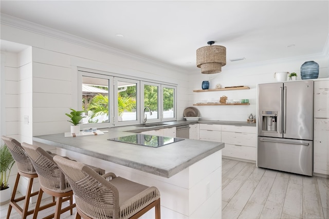 kitchen with a breakfast bar, light wood-type flooring, white cabinetry, kitchen peninsula, and stainless steel appliances