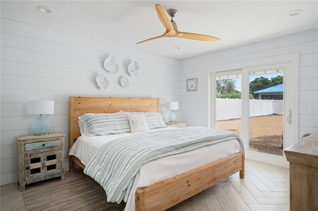 bedroom featuring ceiling fan, access to exterior, parquet floors, and wooden walls