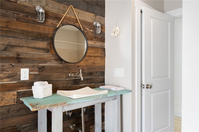 bathroom featuring hardwood / wood-style flooring, sink, and wooden walls