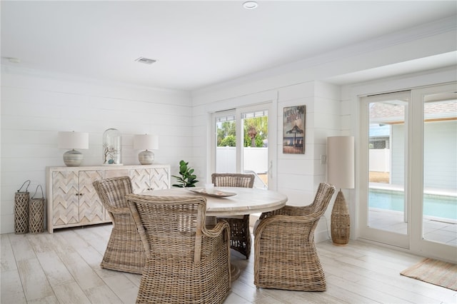 dining area with light wood-type flooring and ornamental molding