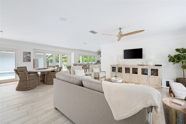 living room with light hardwood / wood-style floors, ceiling fan, and wood walls