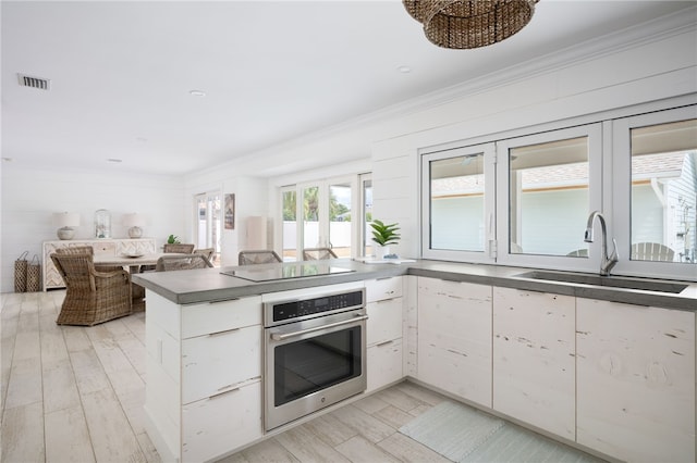 kitchen featuring white cabinets, sink, oven, and ornamental molding