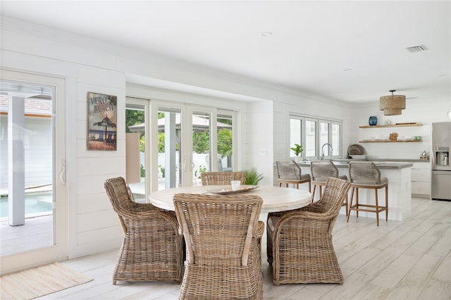 dining area with light wood-type flooring and crown molding