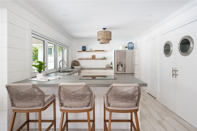 kitchen with kitchen peninsula, crown molding, sink, light hardwood / wood-style flooring, and stainless steel fridge with ice dispenser