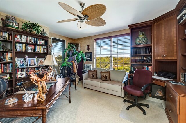 carpeted office space with ceiling fan and built in desk