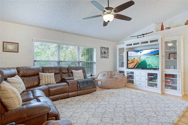 living room featuring a textured ceiling, light hardwood / wood-style floors, ceiling fan, and lofted ceiling