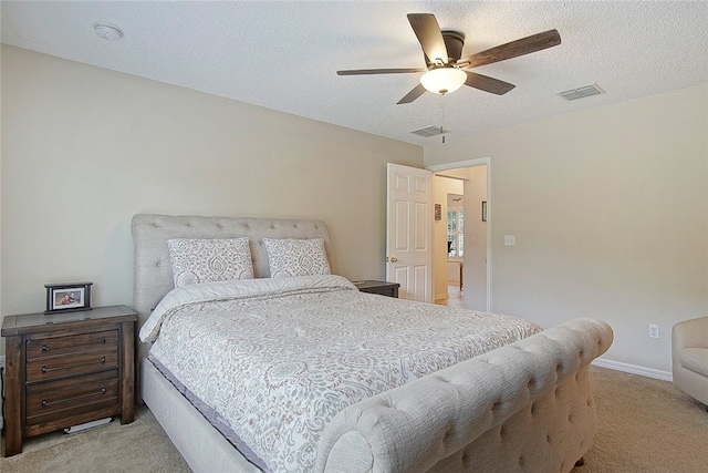 bedroom featuring a textured ceiling, light colored carpet, and ceiling fan