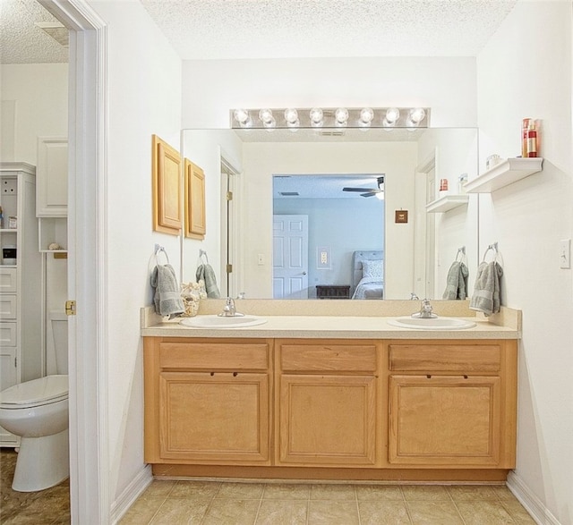 bathroom with tile patterned floors, vanity, toilet, and a textured ceiling