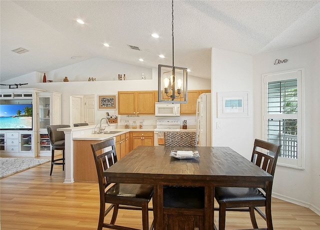 kitchen featuring sink, light hardwood / wood-style flooring, a notable chandelier, decorative light fixtures, and white appliances