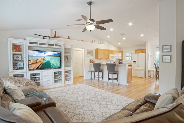 living room with ceiling fan, light hardwood / wood-style floors, and high vaulted ceiling