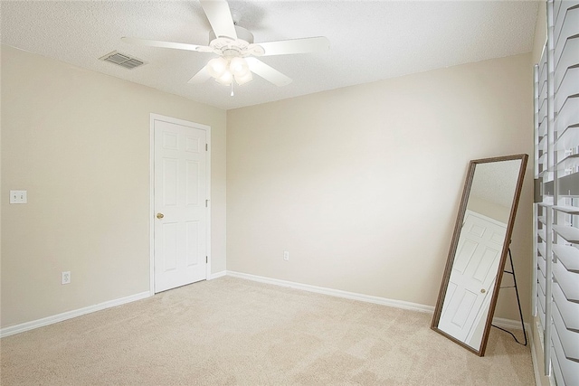 unfurnished bedroom with a textured ceiling, ceiling fan, and light carpet