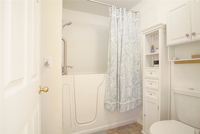 bathroom with shower / bath combination with curtain, toilet, and a textured ceiling