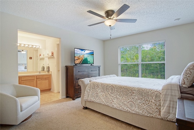 carpeted bedroom with ensuite bath, ceiling fan, and a textured ceiling