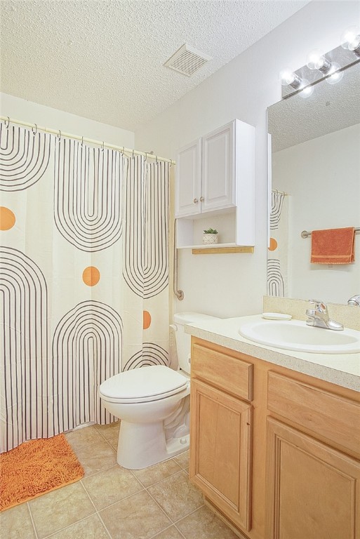 bathroom with tile patterned flooring, vanity, toilet, and a textured ceiling