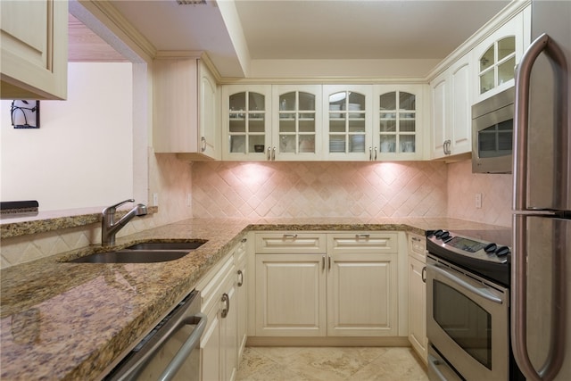 kitchen featuring sink, cream cabinetry, stainless steel appliances, and light stone counters