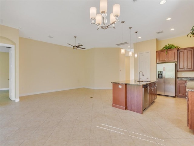 kitchen with light tile patterned flooring, stone countertops, hanging light fixtures, a center island with sink, and stainless steel appliances