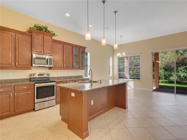 kitchen with sink, light stone counters, an island with sink, pendant lighting, and stainless steel appliances