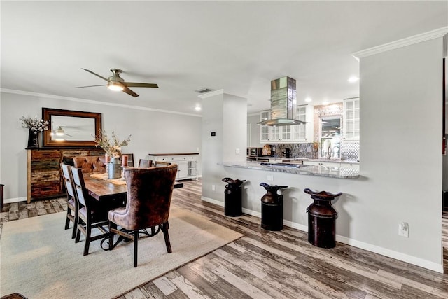 dining area featuring hardwood / wood-style floors, ceiling fan, and ornamental molding