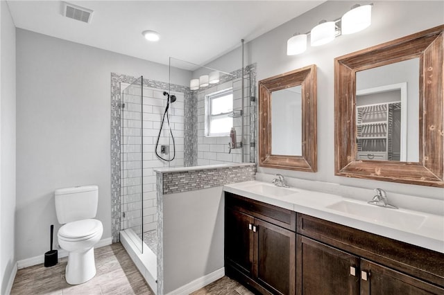 bathroom with vanity, toilet, and tiled shower