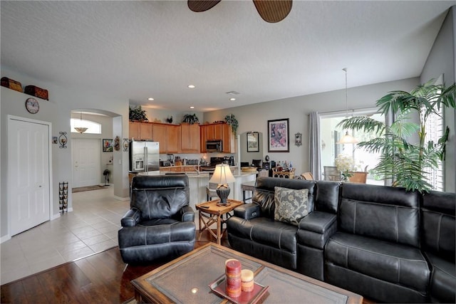 living room featuring ceiling fan, light hardwood / wood-style floors, and a textured ceiling