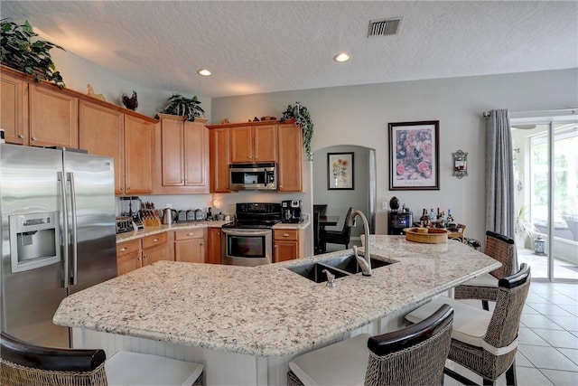 kitchen with an island with sink, appliances with stainless steel finishes, and a breakfast bar area