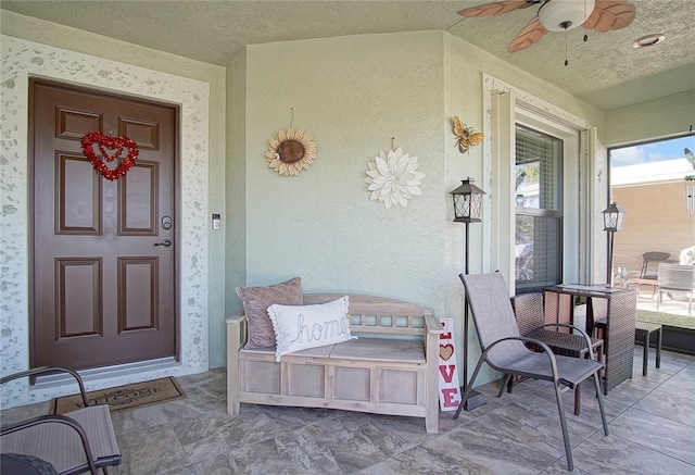 view of exterior entry with stucco siding, a porch, and a ceiling fan