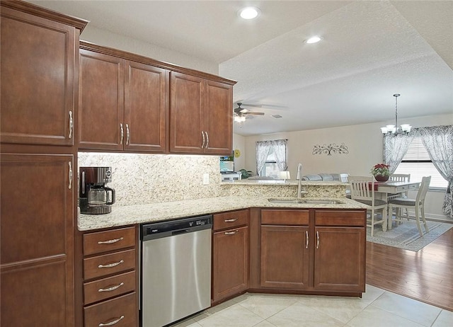 kitchen featuring light stone counters, a peninsula, a sink, dishwasher, and ceiling fan with notable chandelier