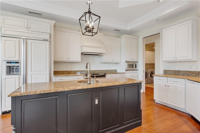 104 Island Plantation Ter Unit 304, Vero Beach, FL 32963 - kitchen with visible vents, a sink, premium range hood, washing machine and clothes dryer, and white cabinets