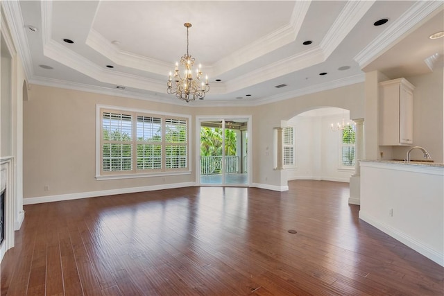 104 Island Plantation Ter Unit 304, Vero Beach, FL 32963 - unfurnished living room featuring arched walkways, a raised ceiling, a chandelier, and dark wood-style floors