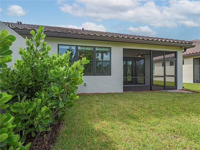 back of house featuring a sunroom, a yard, and ceiling fan