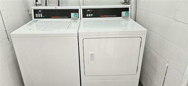 laundry area with concrete block wall and washer and clothes dryer