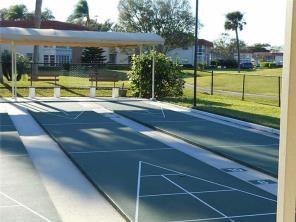 view of property's community featuring shuffleboard and a yard