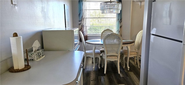 dining space with dark wood-type flooring and a notable chandelier