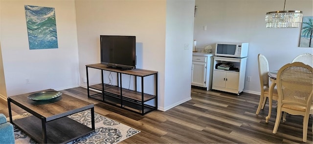 interior space featuring baseboards, a notable chandelier, and dark wood finished floors