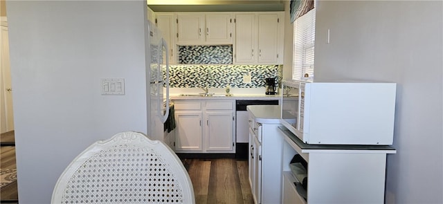 kitchen with white appliances, a sink, decorative backsplash, dark wood-type flooring, and white cabinetry