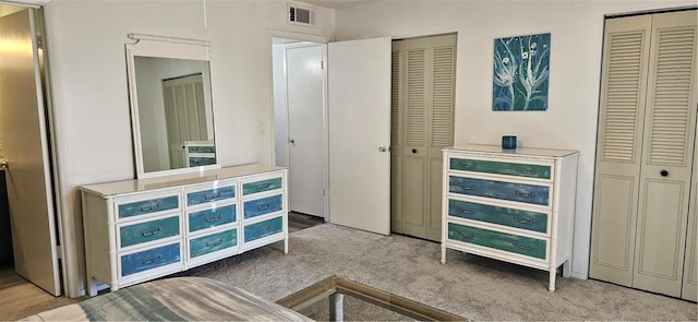 carpeted bedroom featuring visible vents and multiple closets