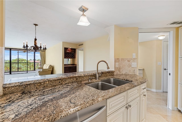 kitchen with sink, light tile patterned floors, hanging light fixtures, a chandelier, and stone counters