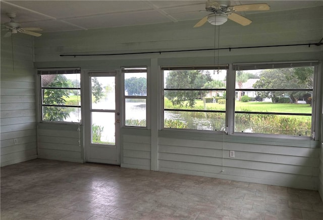 unfurnished sunroom featuring ceiling fan and a water view