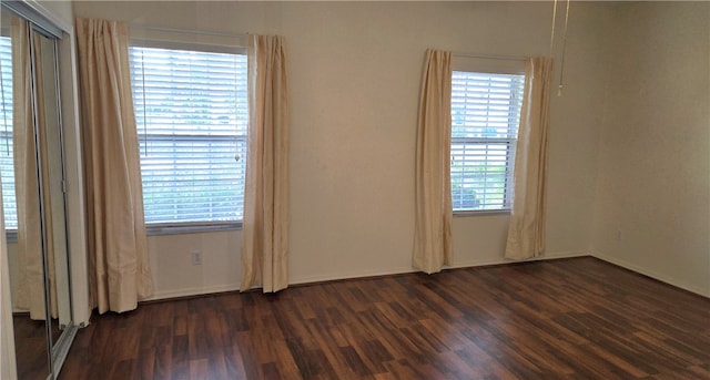 empty room featuring a wealth of natural light and dark hardwood / wood-style floors