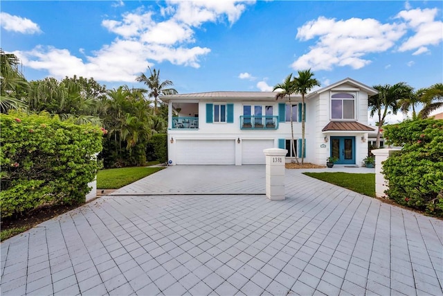 view of front of house with french doors, a balcony, a front yard, and a garage