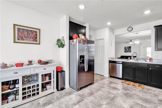 kitchen featuring appliances with stainless steel finishes, sink, a textured ceiling, and decorative light fixtures