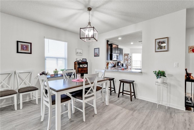 dining space with a textured ceiling and light wood-type flooring