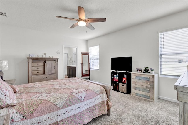 bedroom featuring ceiling fan, carpet, ensuite bathroom, and a textured ceiling