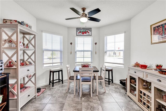 dining space with ceiling fan and a textured ceiling