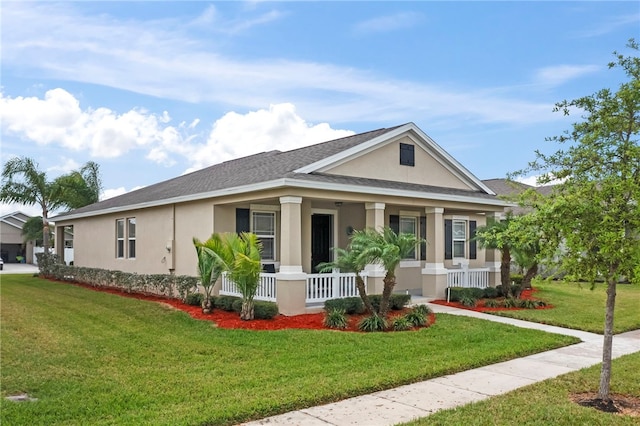 view of front of property with a porch, a front lawn, roof with shingles, and stucco siding