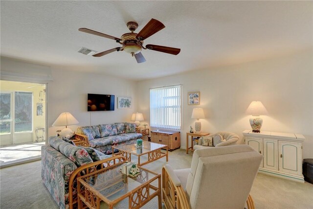 living room with ceiling fan, light colored carpet, and a textured ceiling