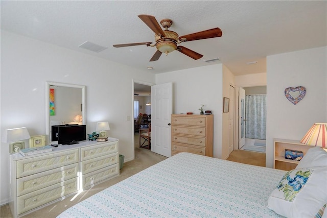 bedroom featuring light carpet, ensuite bathroom, and ceiling fan