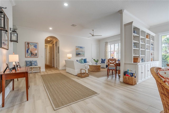 sitting room featuring ornamental molding, arched walkways, visible vents, and light wood finished floors