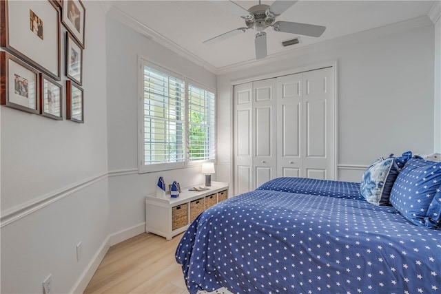 bedroom with a ceiling fan, visible vents, a closet, light wood finished floors, and crown molding