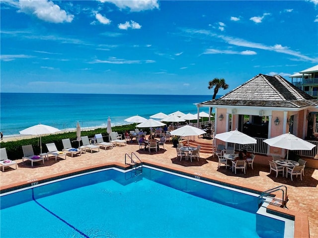 pool with outdoor dining area, a patio area, fence, and a water view